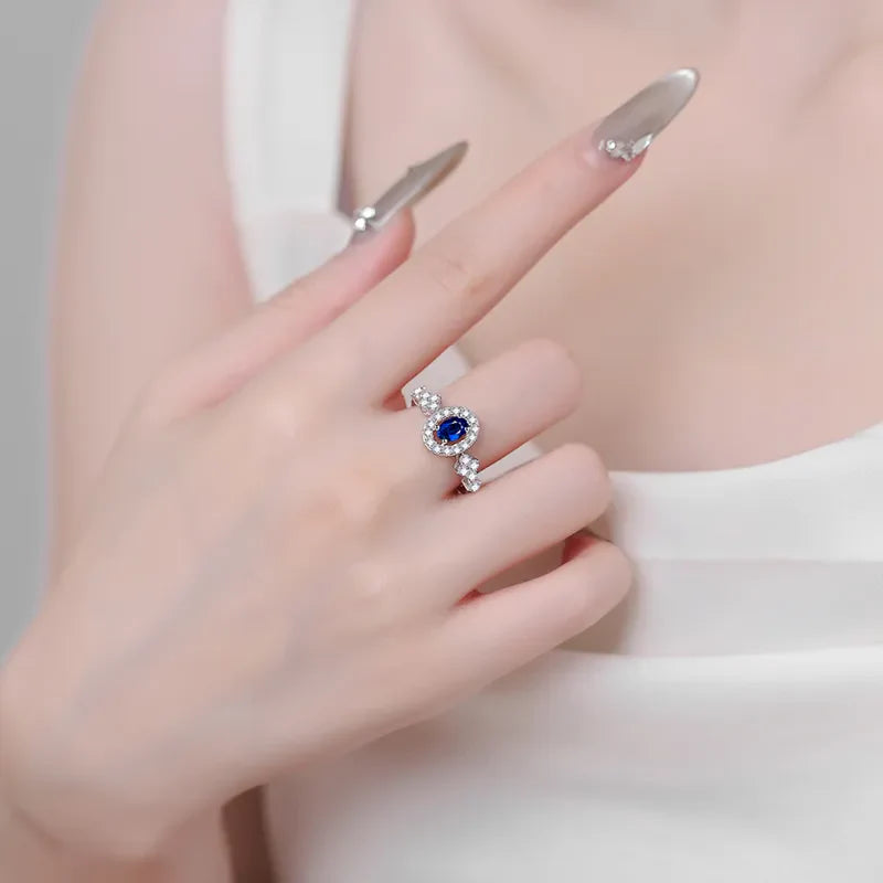 Silver sapphire halo and diamond cluster ring on a hand