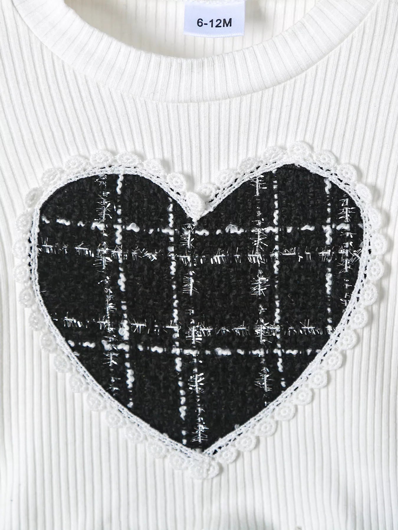 White ribbed baby top with black plaid heart applique and lace trim.