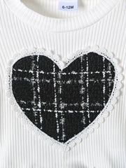 White ribbed baby top with black plaid heart applique and lace trim.