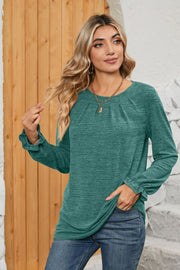 Teal knit top with pleated yoke and ruffled cuffs, crew neck, long sleeves.