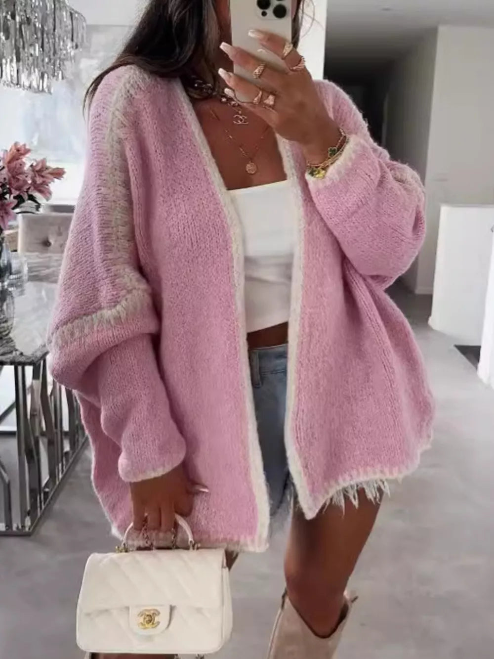 Oversized pink cardigan with contrast trim and frayed hem, worn open over a white top.