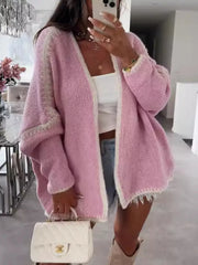 Oversized pink cardigan with contrast trim and frayed hem, worn open over a white top.