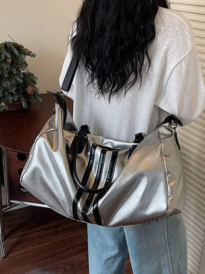 Sleek silver metallic duffle bag with black stripes and handles.