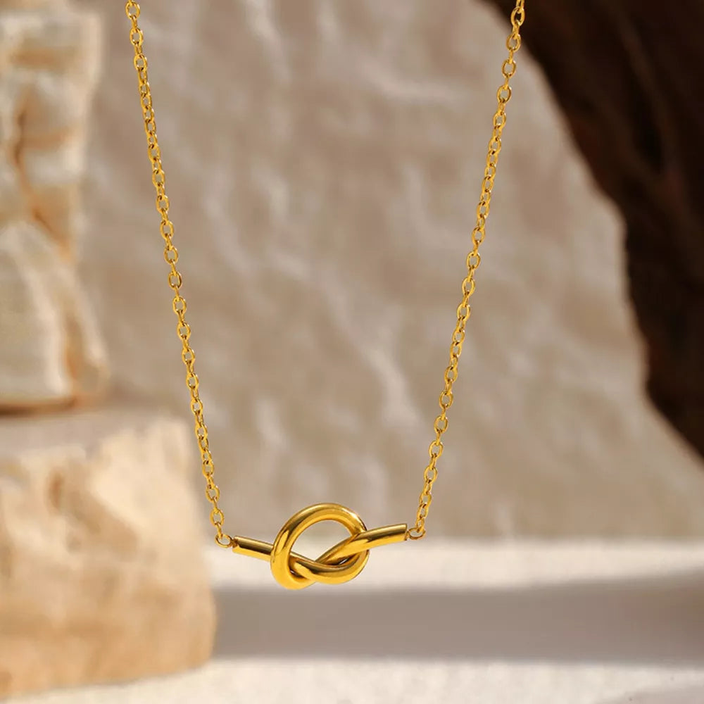 Gold-plated knot pendant necklace with delicate chain.