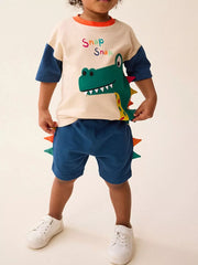 Toddler beige and blue dinosaur applique t-shirt and blue shorts set with colorful spikes.