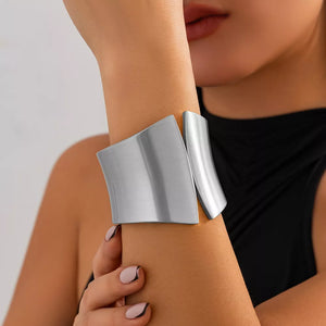 Sculptural silver-toned cuff bracelet with a brushed metal finish and open design.