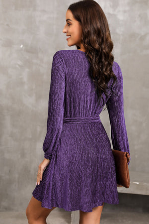 Violet textured pleated mini dress with long sleeves and a waist tie, shown from the back.