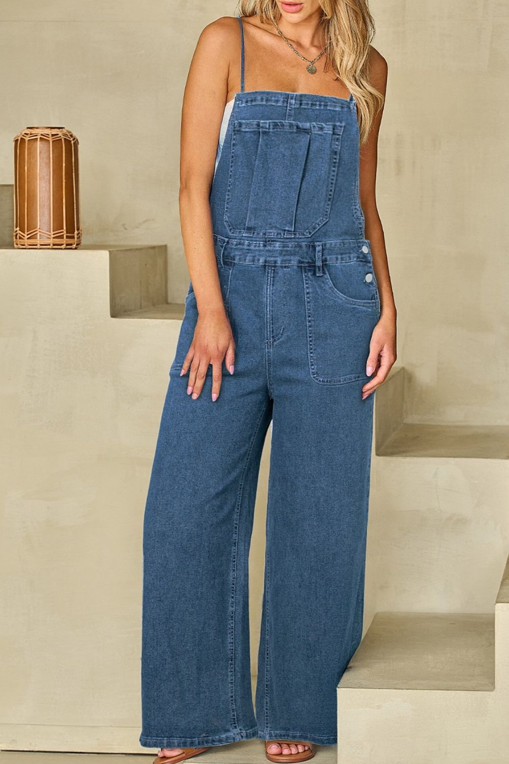 Denim wide-leg overalls in medium wash with adjustable straps and buttoned sides.