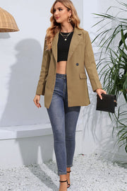 Tan double-breasted blazer with flap pockets and two buttons, worn with a black crop top and jeans.