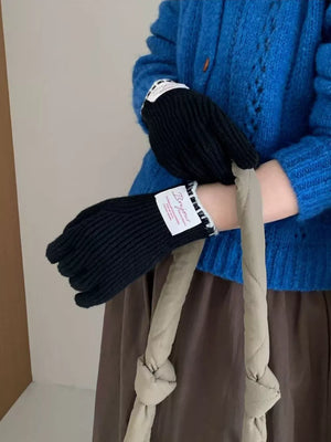 Black ribbed knit gloves with scalloped cuff and white trim detail.