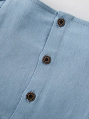 Light blue denim baby dress with wood-look buttons and strawberry embroidery detail.