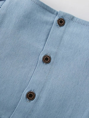 Light blue denim baby dress with wood-look buttons and strawberry embroidery detail.