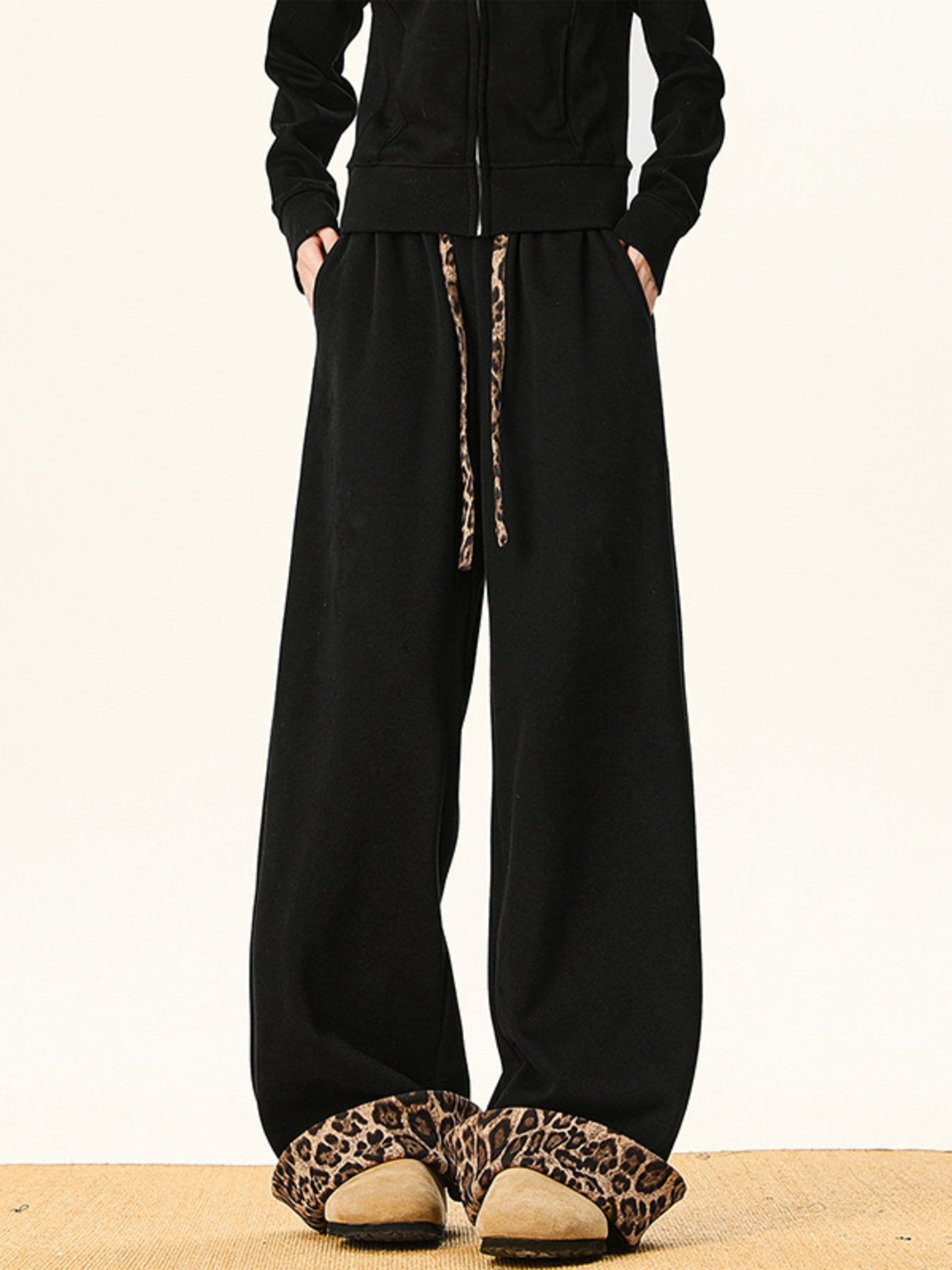 Black sweatpants with wide legs and leopard print drawstring.