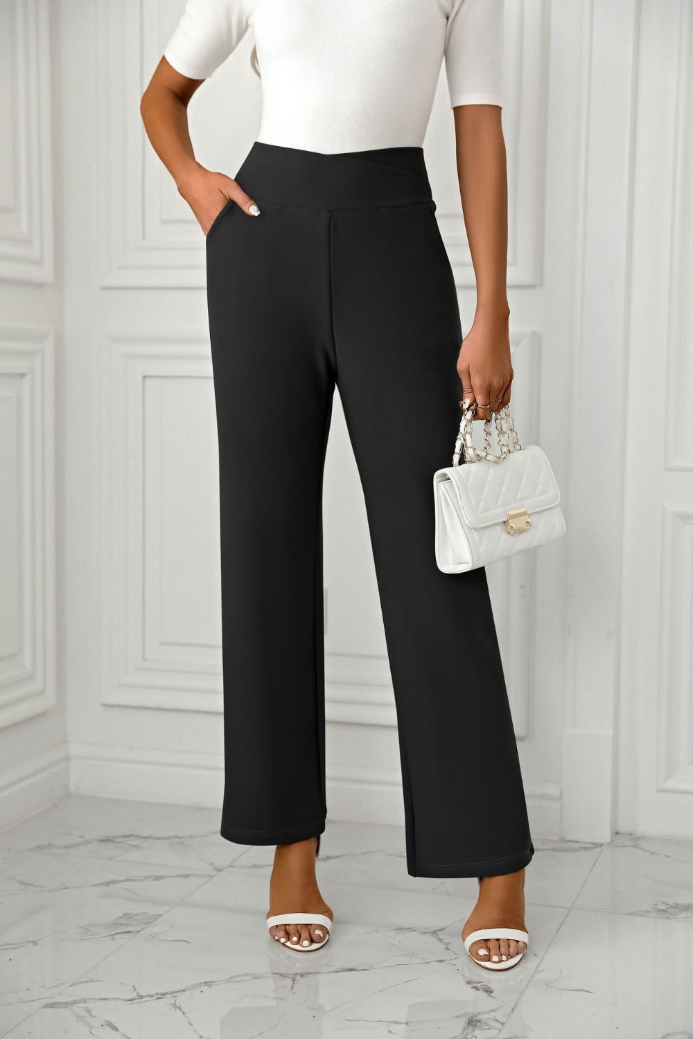 Black wide-leg trousers with a sculpted waist and pockets, styled with a white top and handbag.