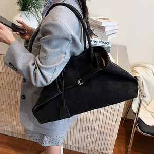 Black suede tote handbag with decorative strap detail and silver buckle.
