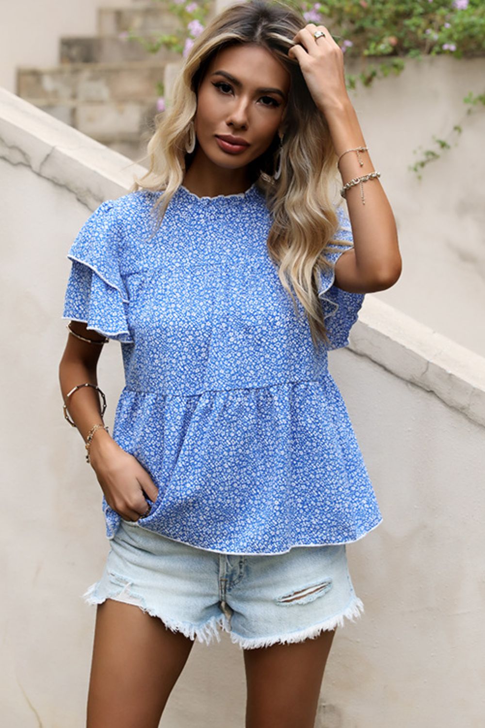 Sky blue floral peplum blouse with ruffled short sleeves and mock neck.