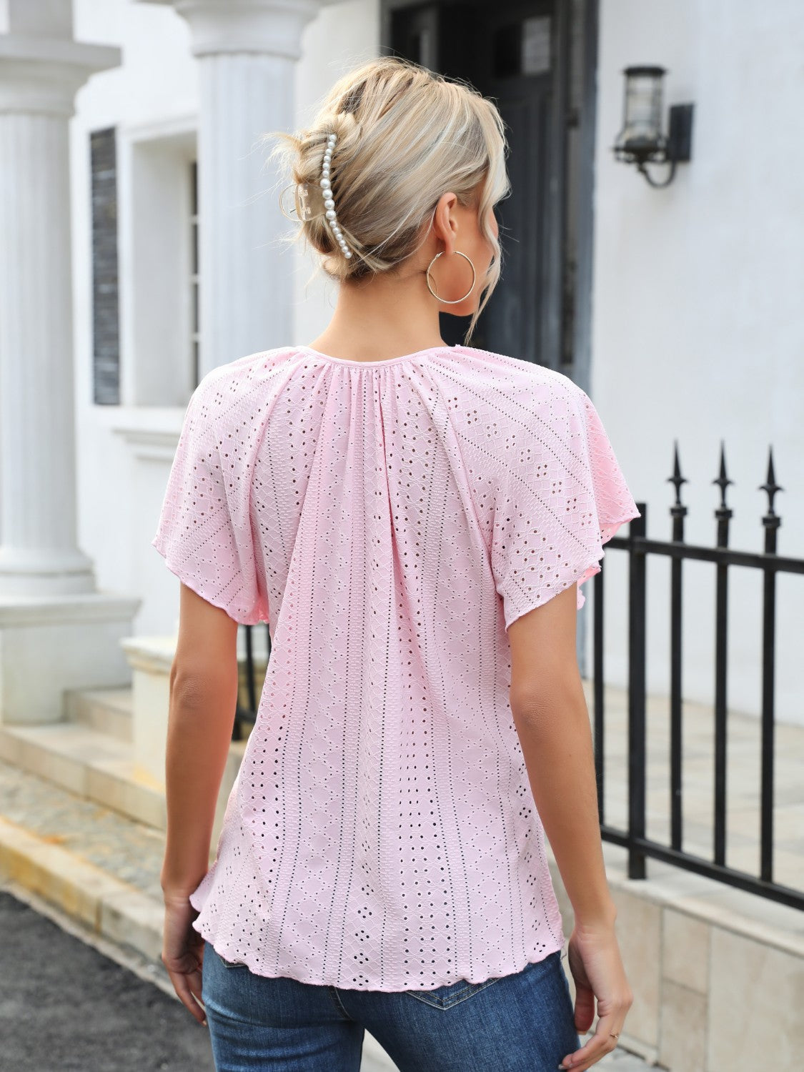 Blush pink perforated tie-neck blouse with flutter sleeves and scalloped hem