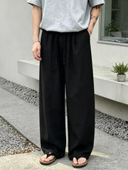 Black wide-leg sweatpants with drawstring waist and pockets, styled casually.
