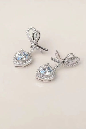 Silver bow-adorned heart moissanite drop earrings with pavé accents.