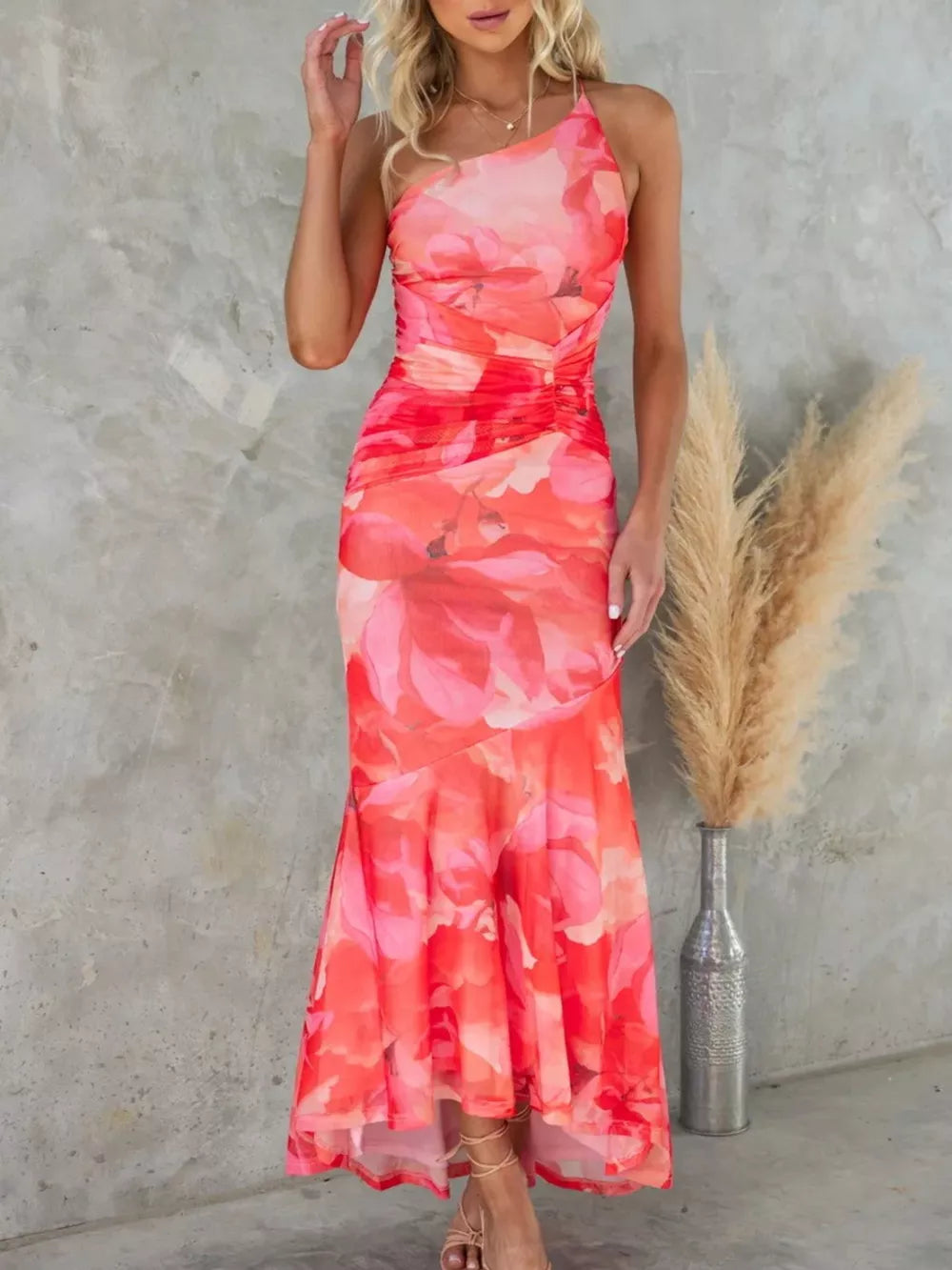 Maxi dress with one-shoulder neckline, ruched bodice, and floral print in red and pink.