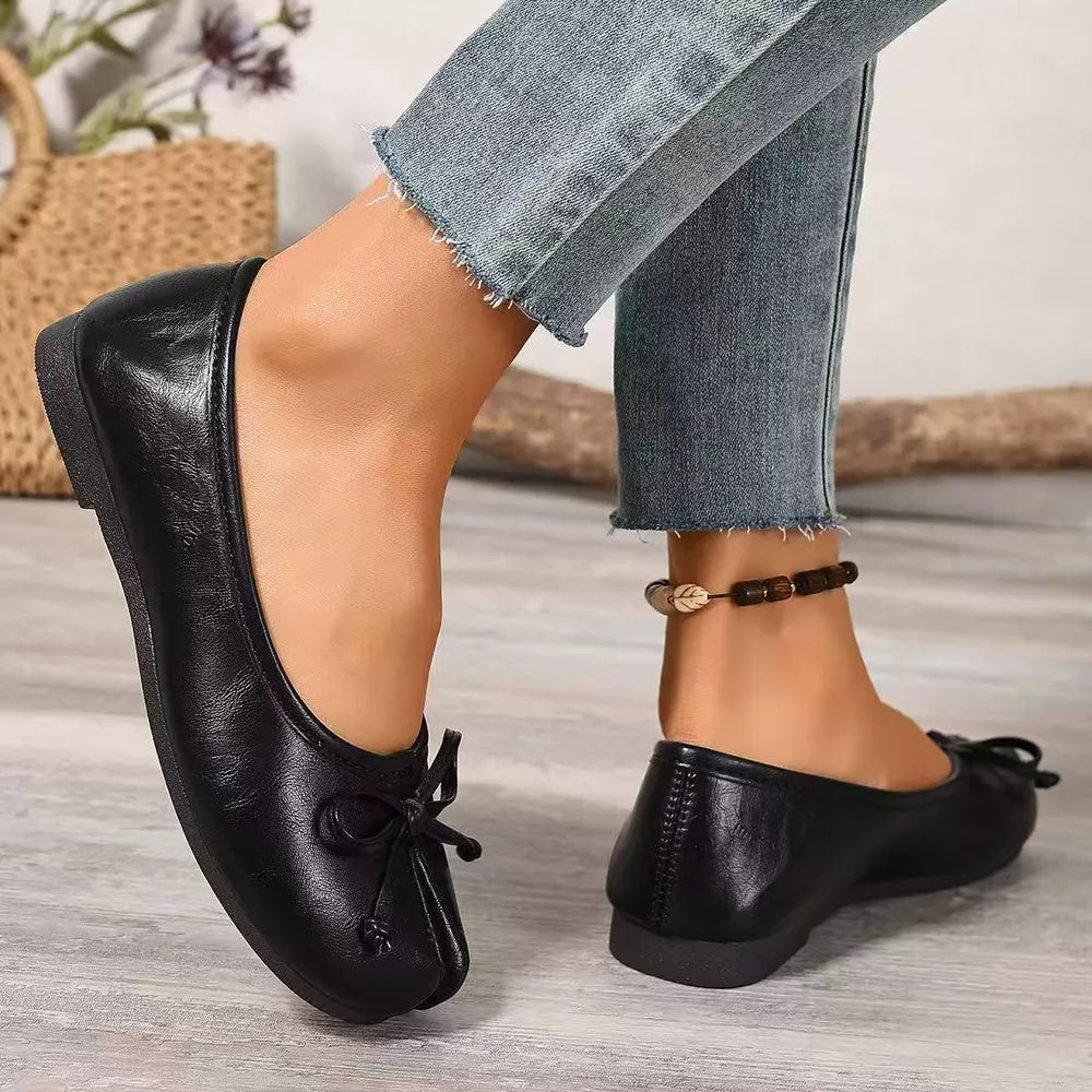 Black Tabi slip-on flats with bow detail and split toe, worn with jeans.