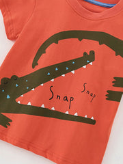 Coral cotton toddler t-shirt with a playful green crocodile graphic and "Snap" text.