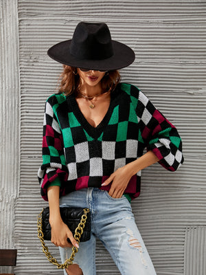 Geometric checkerboard V-neck knit sweater with puff sleeves in black, green, white, and maroon.