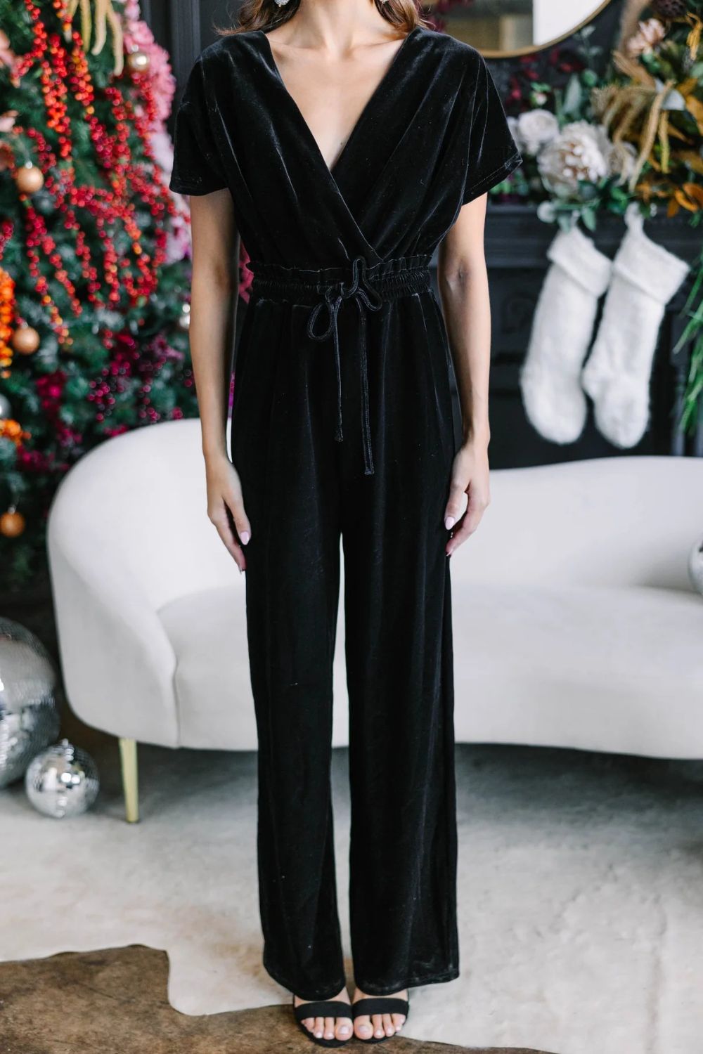 Black velvet wrap bodice wide-leg jumpsuit with drawstring waist and short sleeves.