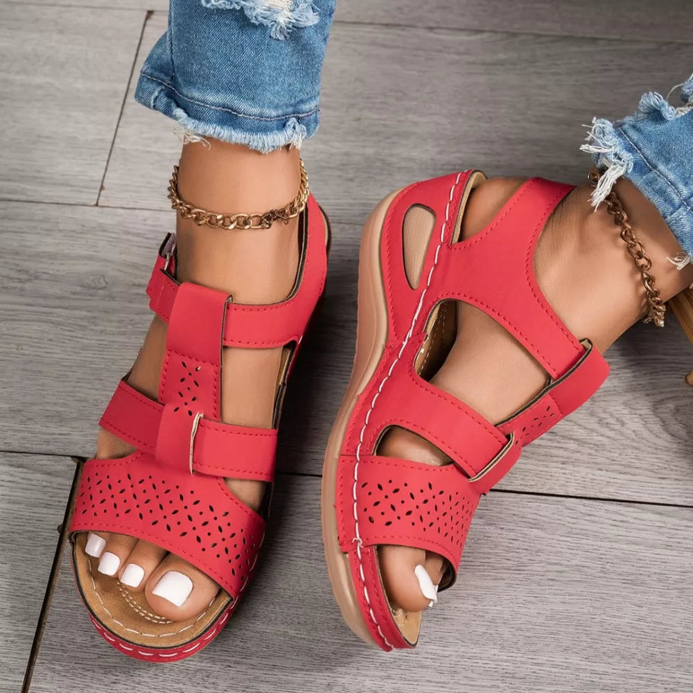 Red perforated mid-wedge sandals with adjustable straps and white stitching detail.