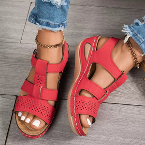 Red perforated mid-wedge sandals with adjustable straps and white stitching detail.