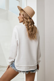White sweatshirt with asymmetric hemline and raw edge detail, styled with denim shorts.