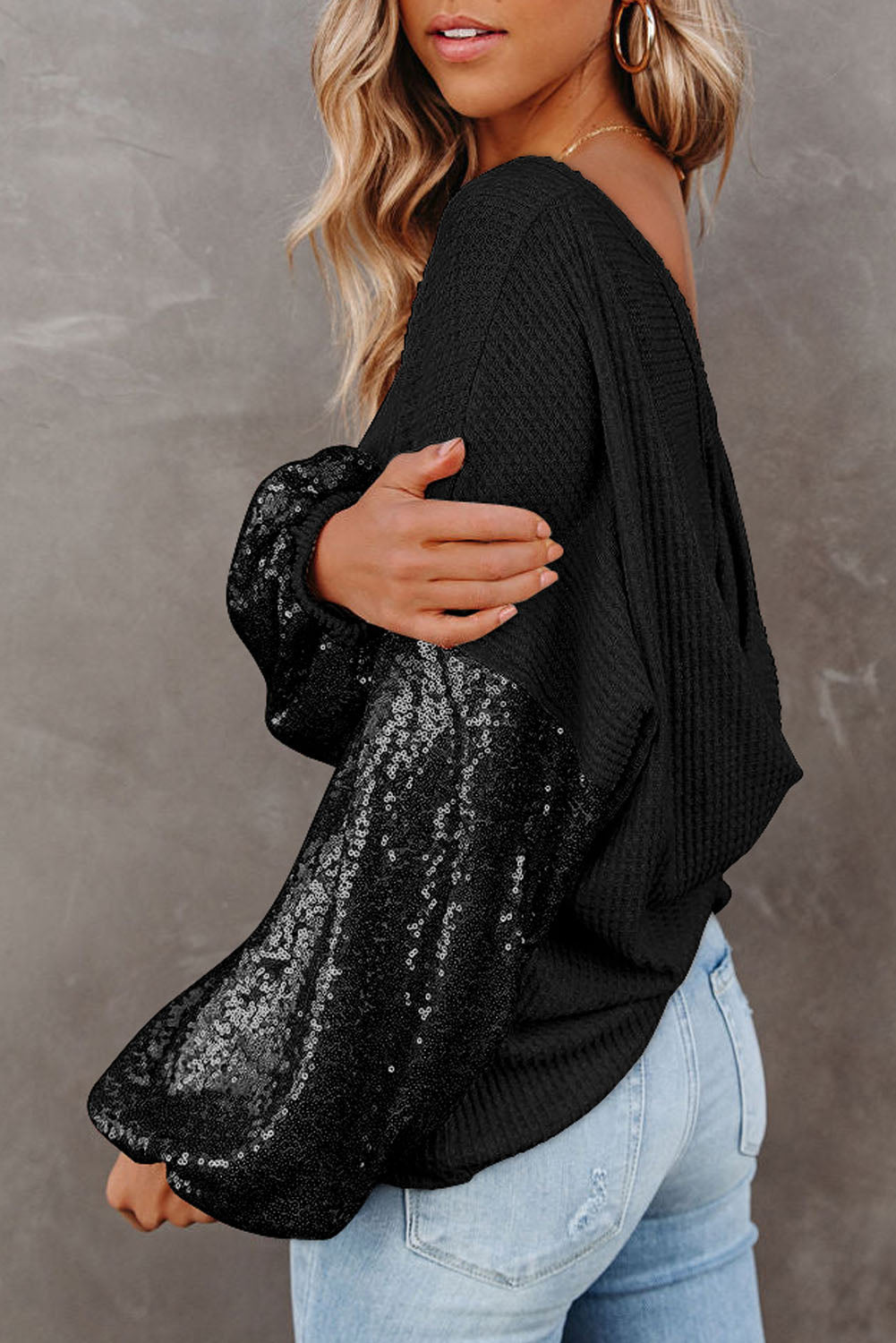 Black waffle knit sweater with sequin sleeves and a relaxed fit.