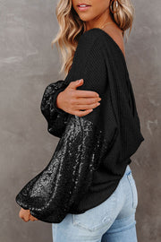 Black waffle knit sweater with sequin sleeves and a relaxed fit.