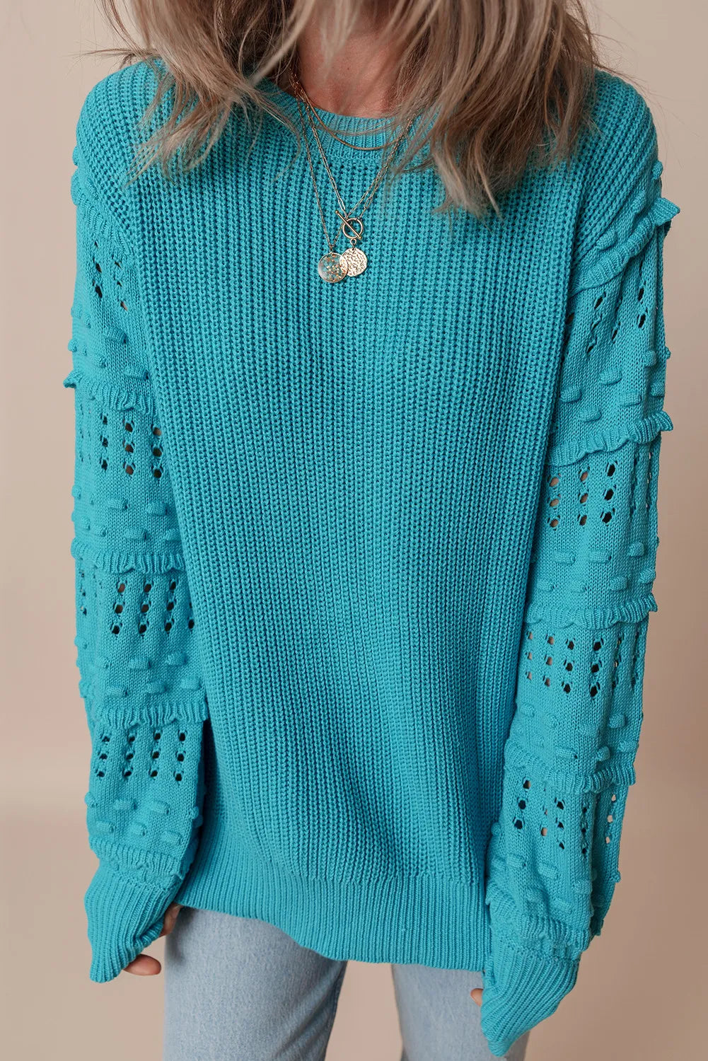 Turquoise knit sweater with textured cutout sleeves and crew neck.