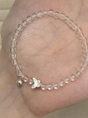 Clear crystal bead bracelet with silver butterfly charm and bell charm.