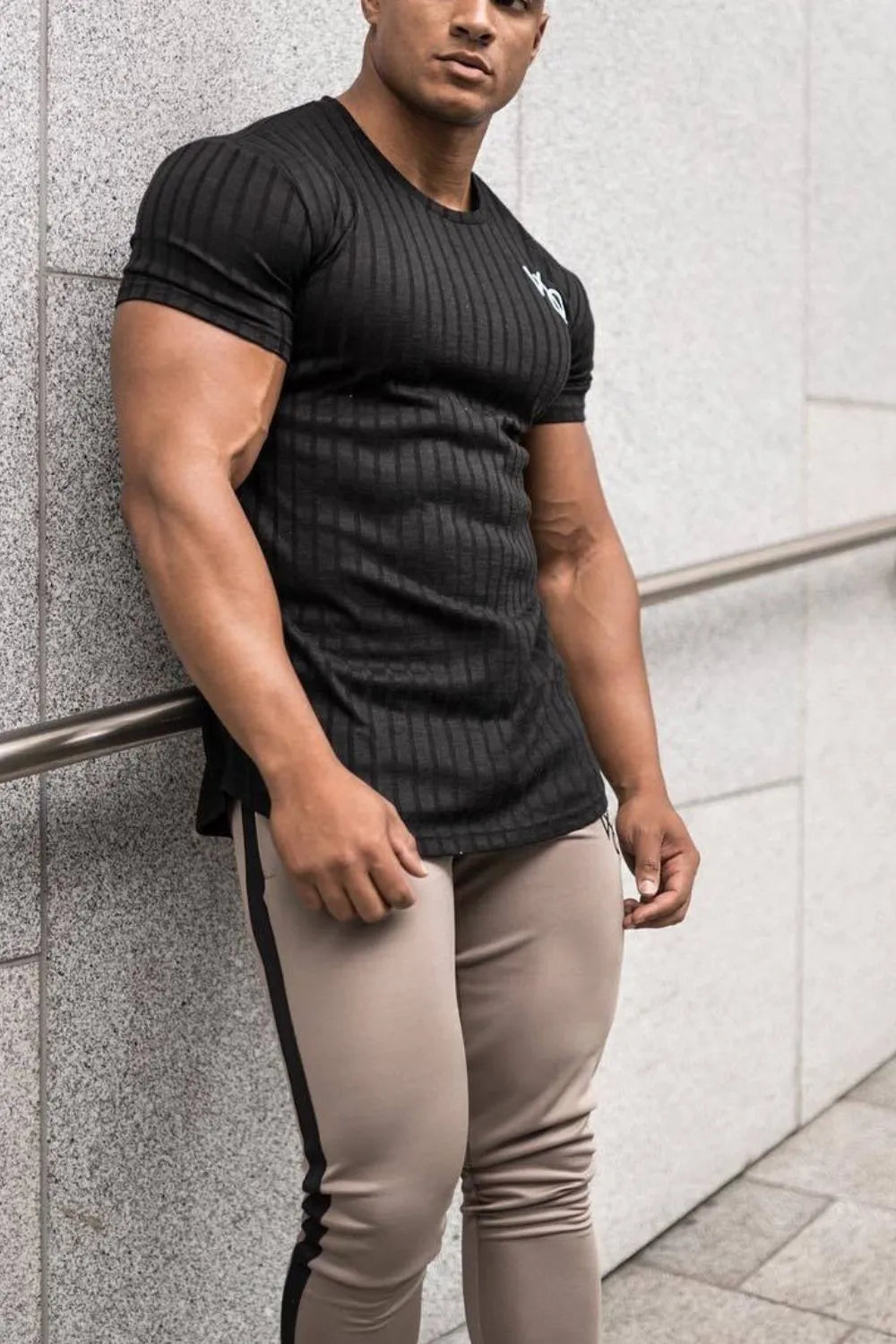 Black ribbed t-shirt with short sleeves and a subtle logo detail on the chest.
