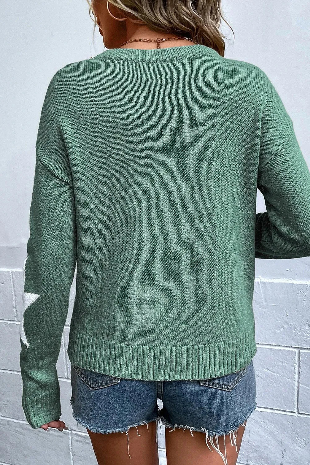 Sage knit jumper with white stars on the sleeve, crew neck, long sleeves, and ribbed hem.