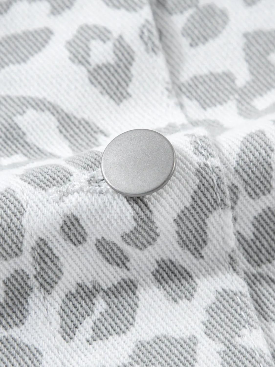 White denim jacket with stone-washed leopard print and button detail.