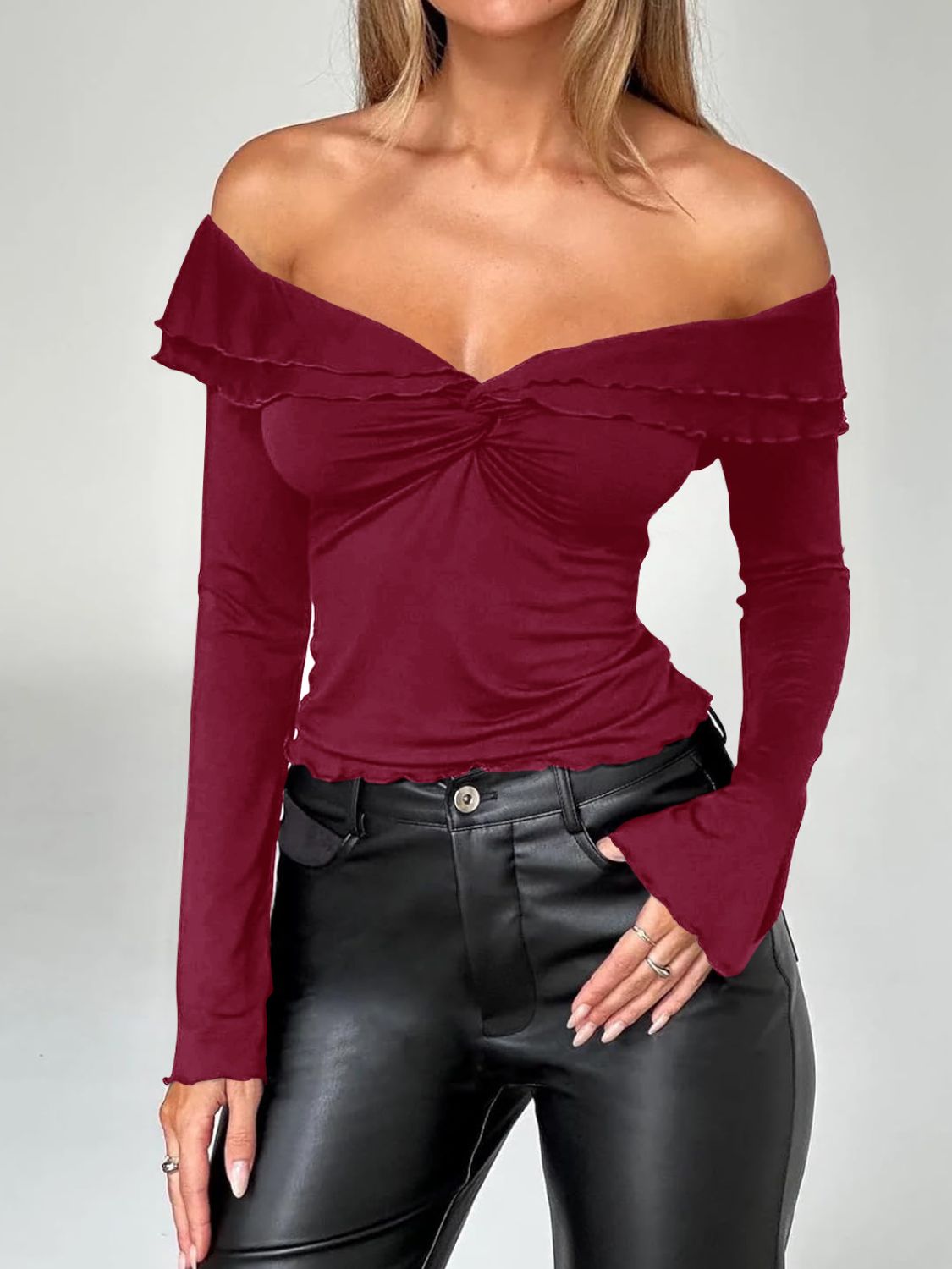 Ruched bodice off-shoulder top in rust with a twisted front and ruffle trim.