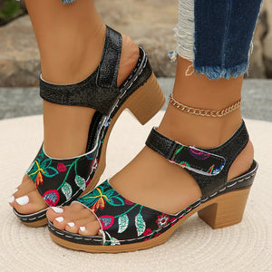 Floral open-toe block heel sandals in black with adjustable strap and embroidered detail.