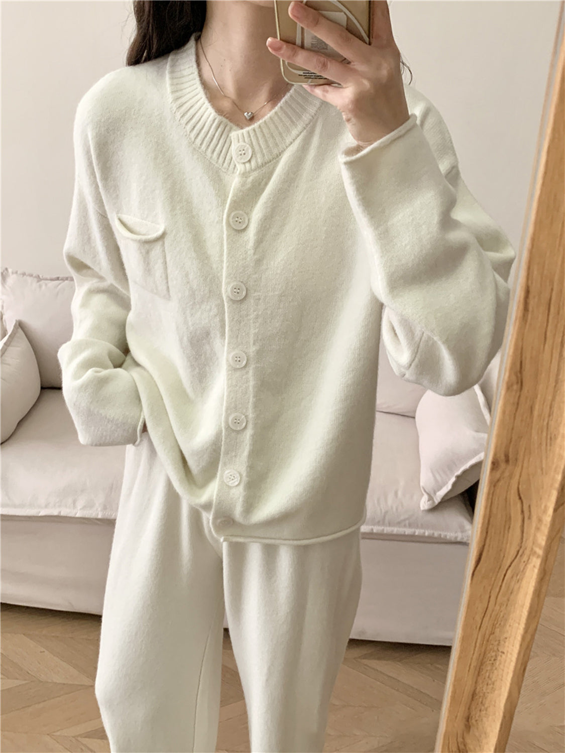 White ribbed knit cardigan with buttons and pocket, paired with wide leg pants.