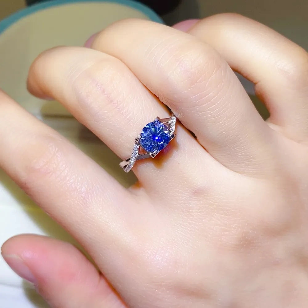 Silver twisted pavé moissanite engagement ring with a blue center stone.
