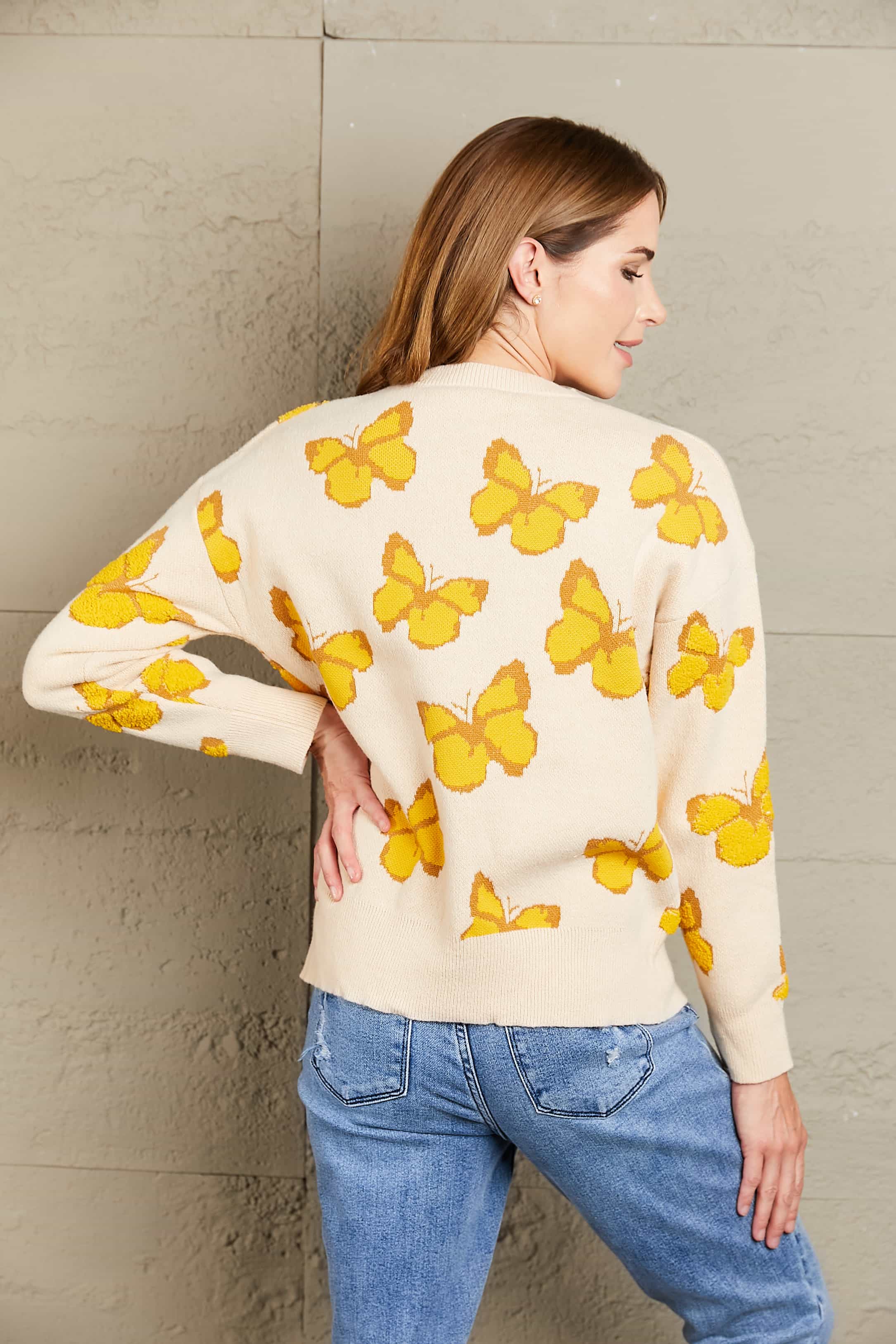 Cream knit crewneck sweater with allover yellow butterfly motif.