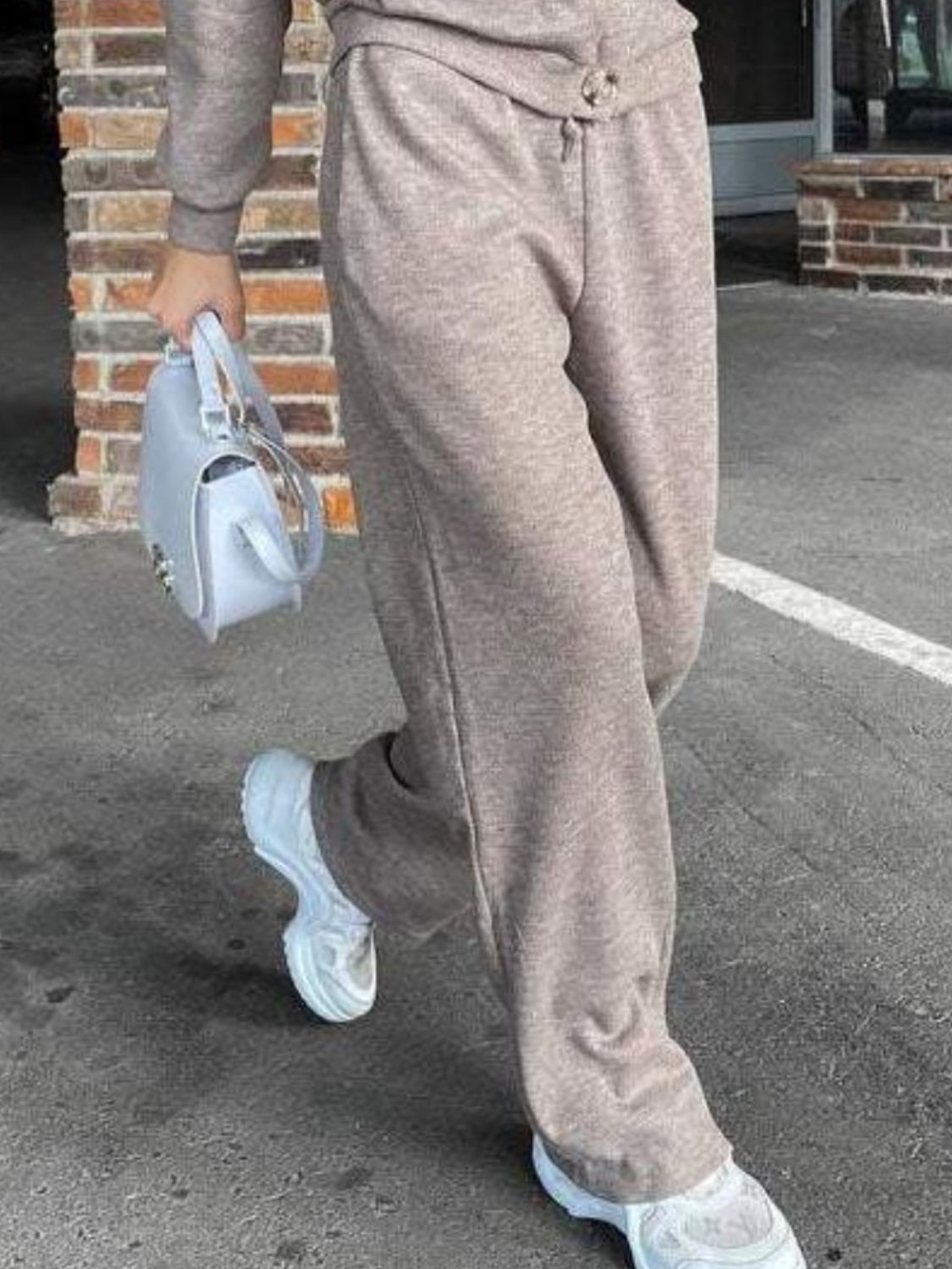 Taupe knit lounge pants with drawstring waist and button detail, worn with white sneakers.