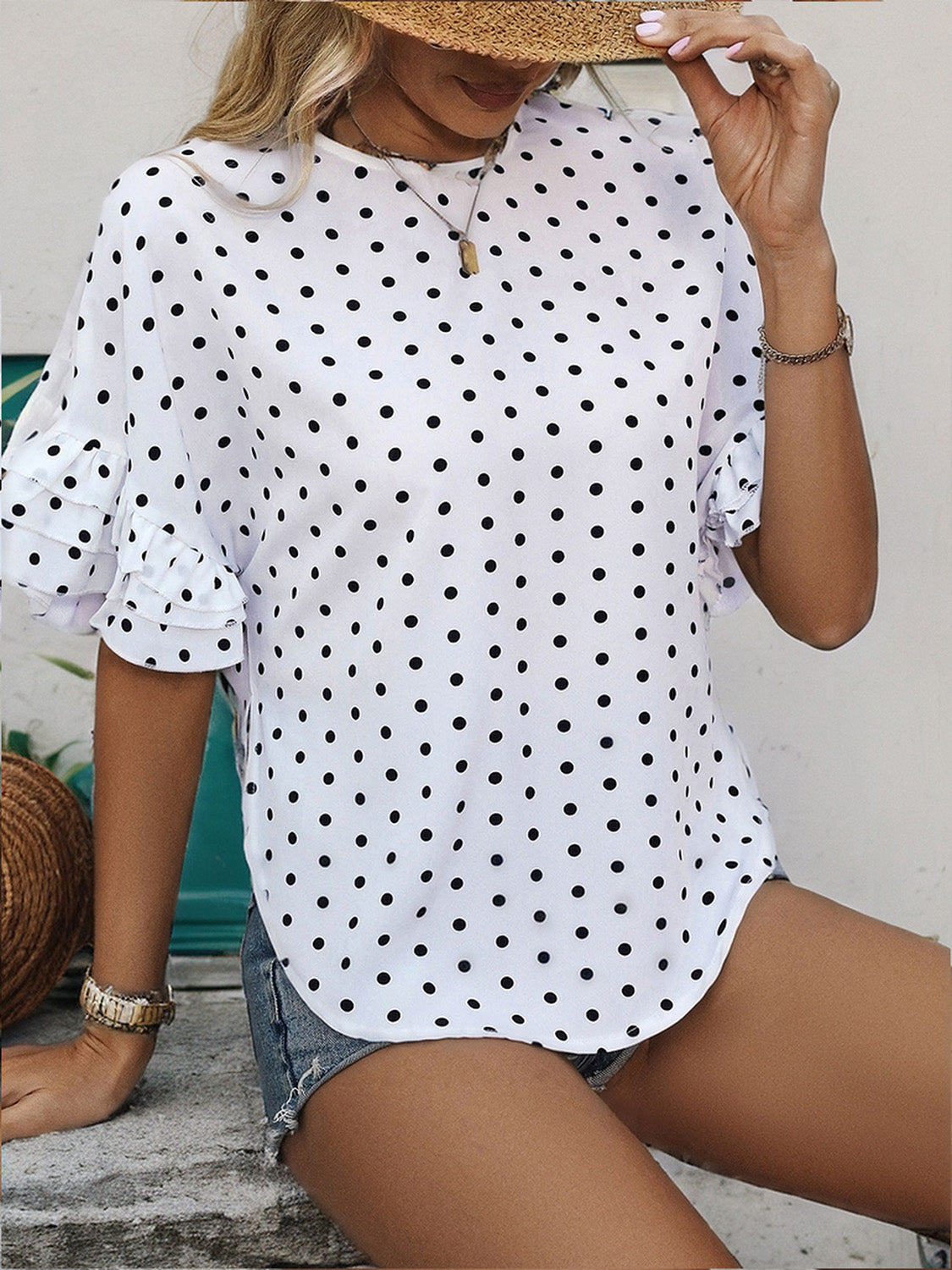 White polka dot blouse with ruffled short sleeves and a keyhole neckline.