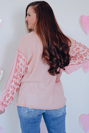 Blush pink waffle knit top with leopard print sleeves and crew neck.