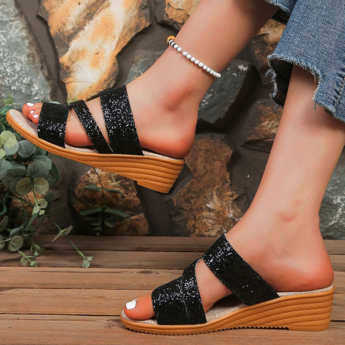 Black sequined wedge sandals with crisscross straps and a wooden wedge heel.