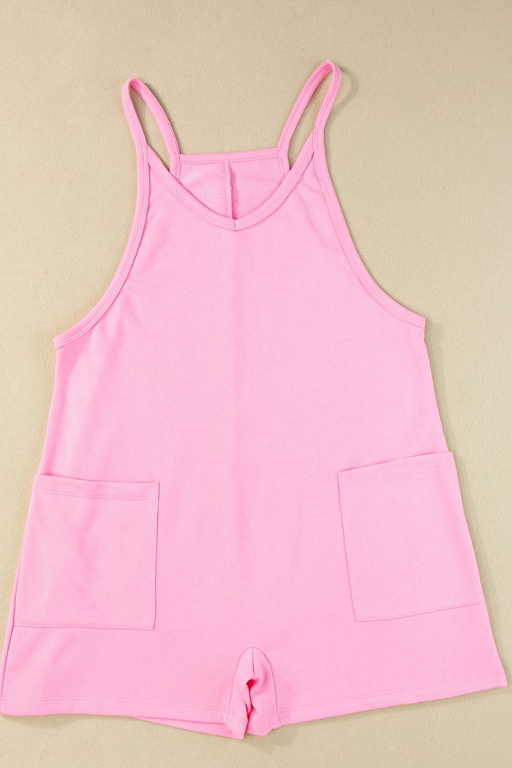 Pink spaghetti strap romper with patch pockets and V-neck.