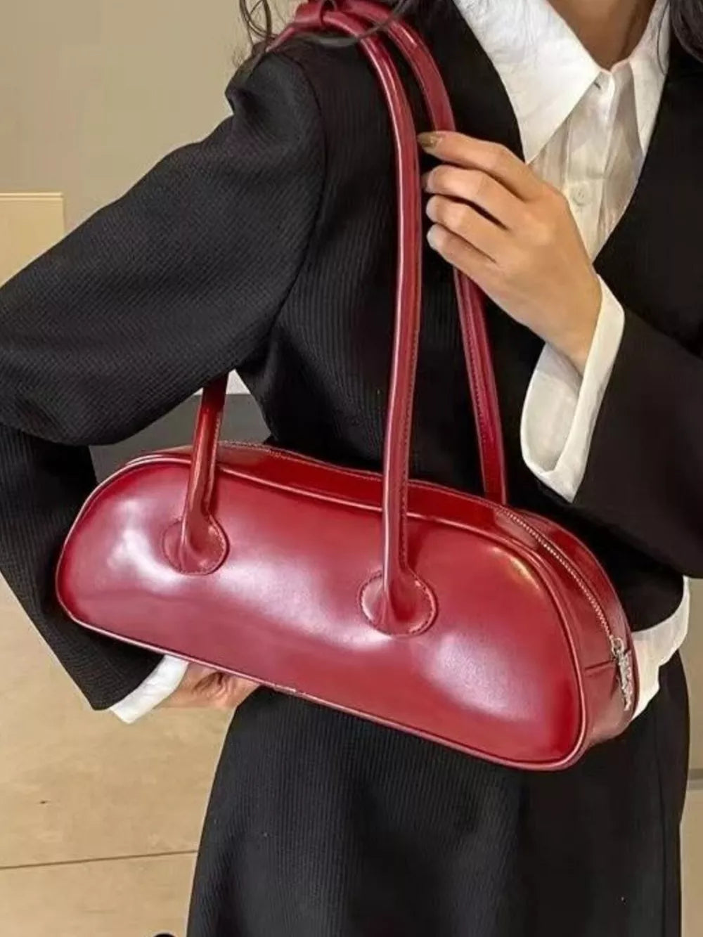 Chic red barrel shoulder bag with double top handles and a zip closure.