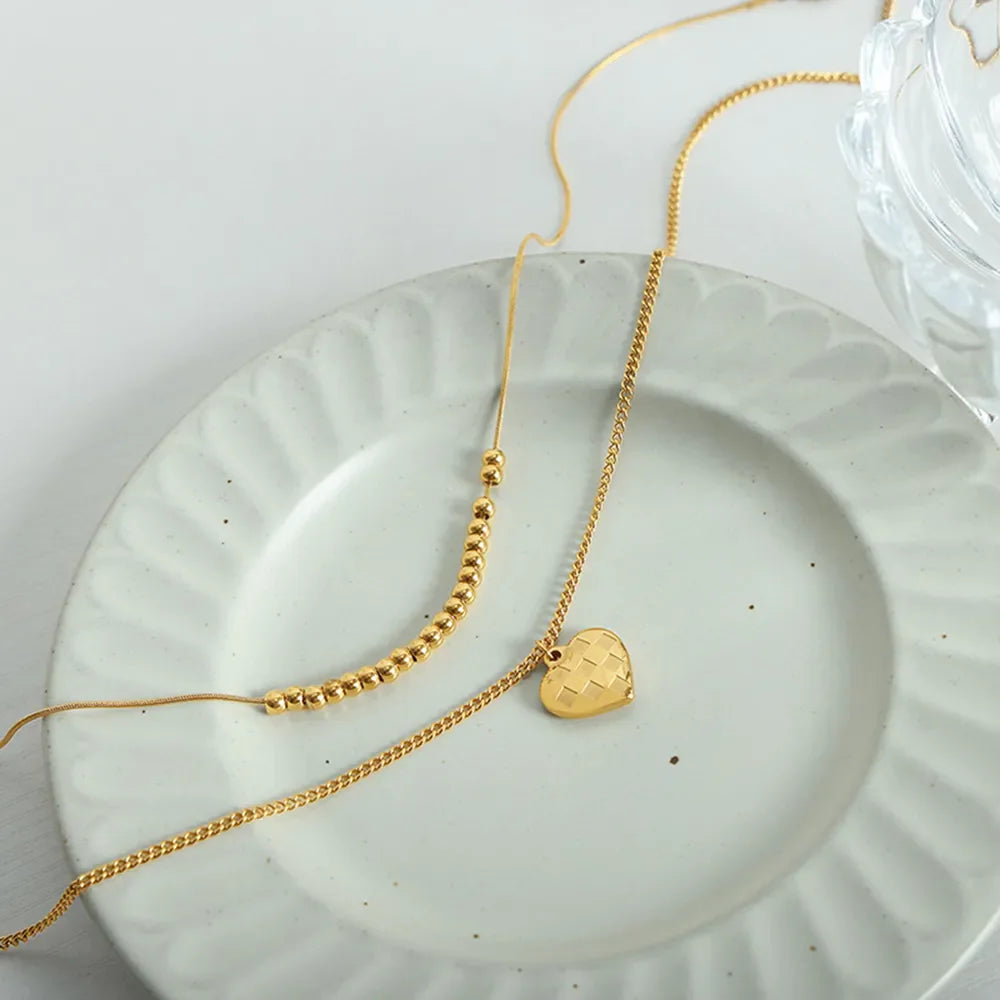 Gold layered necklace with beaded chain and checkered heart charm